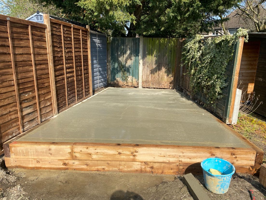 Concrete shed base with timber frame edging in garden