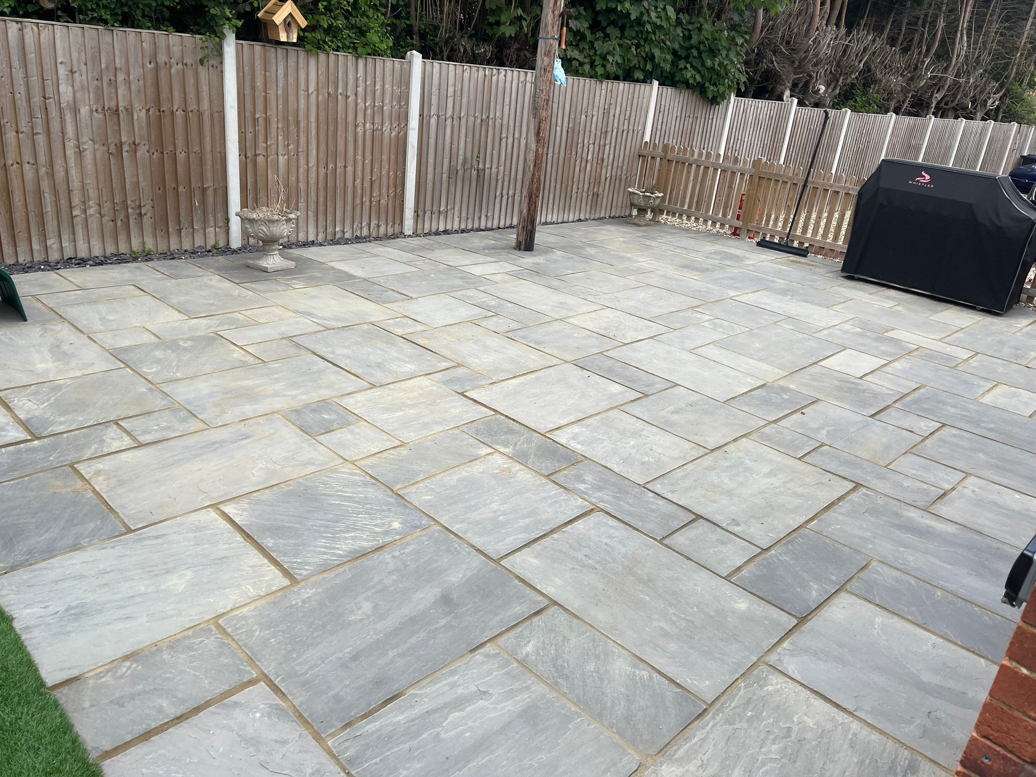 Large Indian stone patio installation with wooden fencing surround