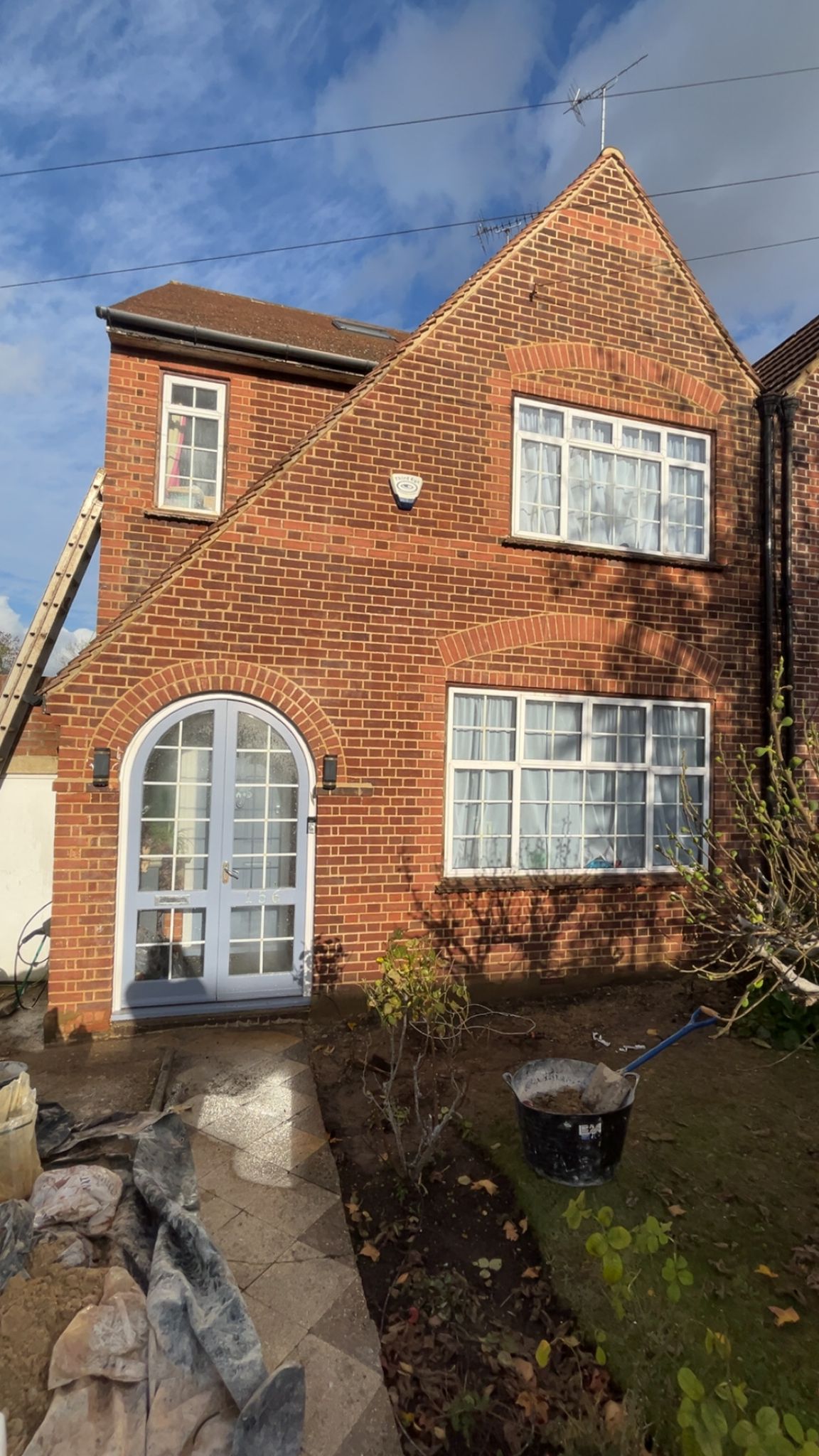 Two-story brick extension with decorative arched doorway and pitched roof